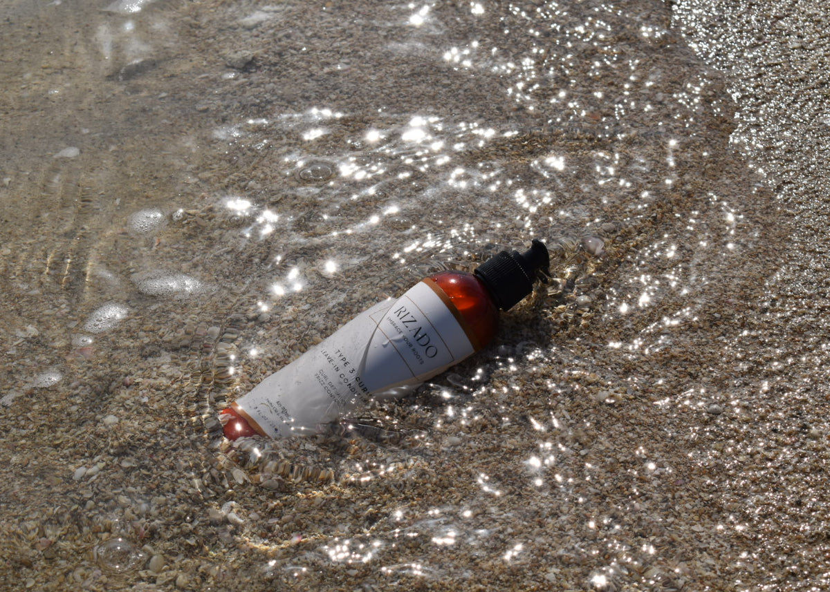 Small bottle with a pump lid on wet sand